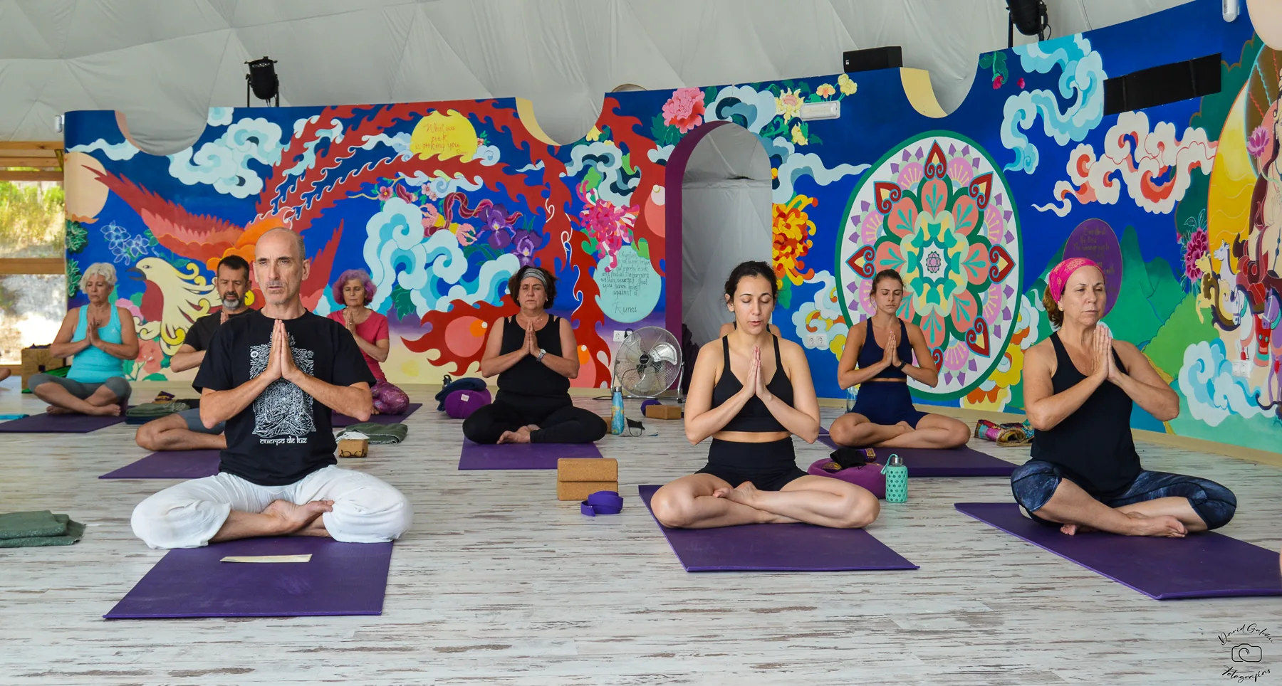 Grupo meditando dentro de un gran domo durante una sesión de yoga
