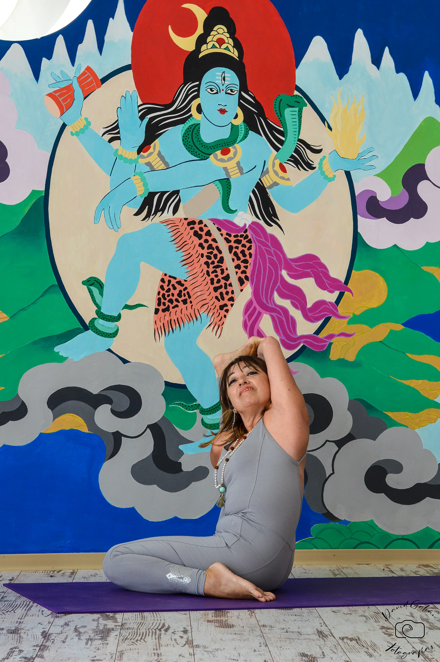 Pilar Valencia sentada frente a un mural de Shiva